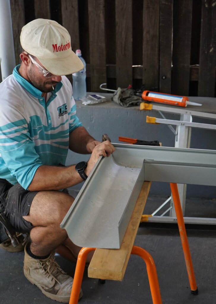 TRG plumber cutting a gutter section to size